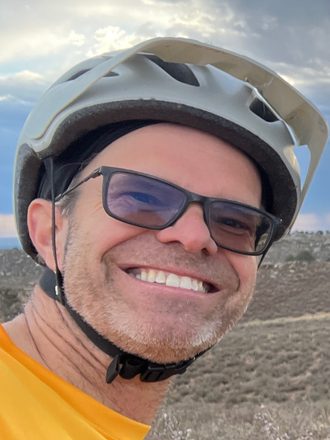 Stan, in a helmet and sunglasses, on a trail at dusk